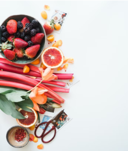 Vibrant display of fresh fruits and vegetables, including apples, oranges, berries, and rhubarb, arranged in a colorful assortment.