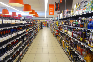 Wide-angle view of a well-stocked grocery store aisle with shelves lined with various food products, ranging from canned goods to cereals.
