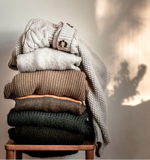 Stack of warm, cozy sweaters indicating comfort and self-care