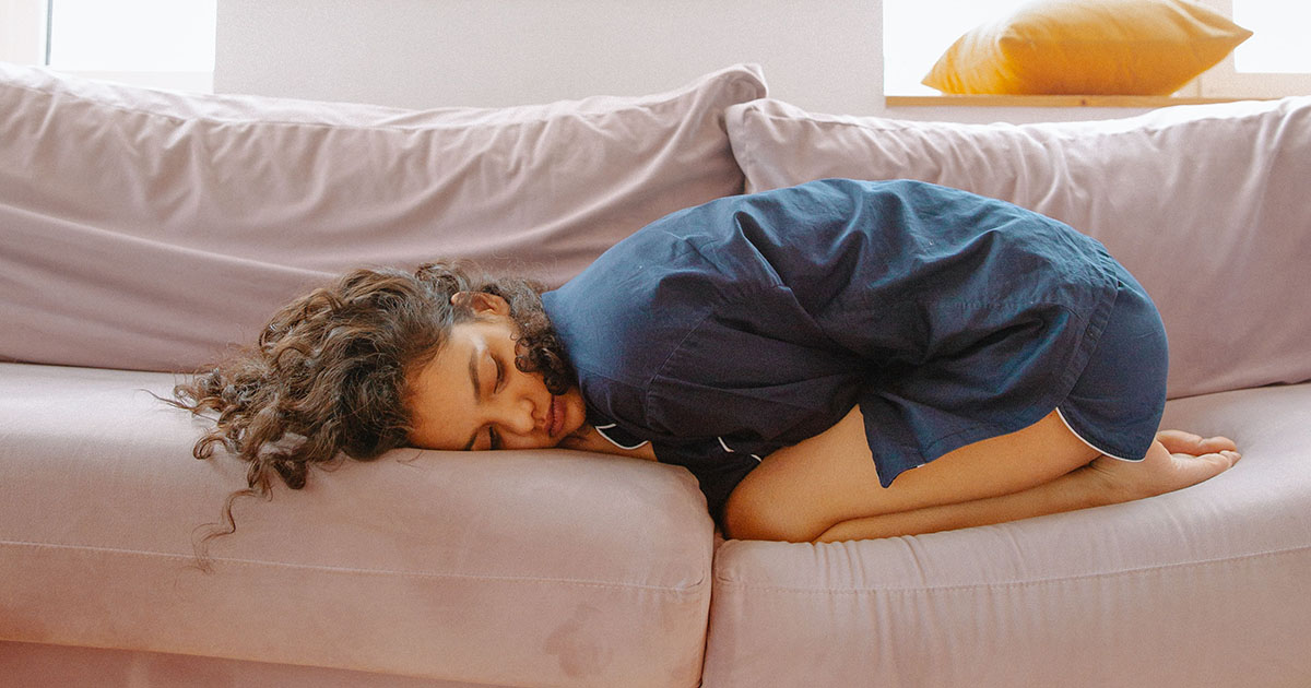 A woman curled up in pain due to her period.