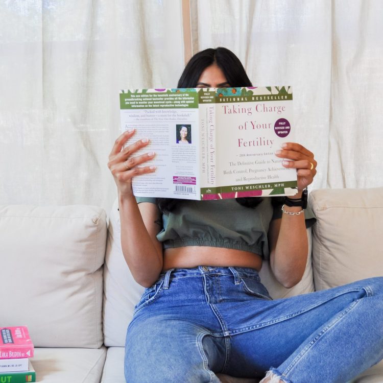 Maiya, Nourishing Balance Registered Dietitian holding up a book called Taking Charge of Your Fertility